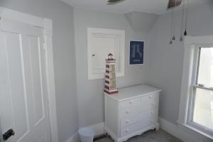 a white bedroom with a dresser and a window at Charlevoix House - The Northside in Charlevoix