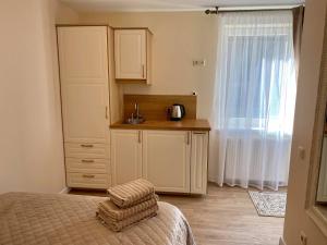 a bedroom with a bed and a kitchen with a window at Vaineikio 8 in Palanga