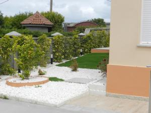 einen Garten mit einem Baum und weißem Kies in der Unterkunft APARTAMENTOS COSTA XUÑO in Porto do Son + 9 Fotos