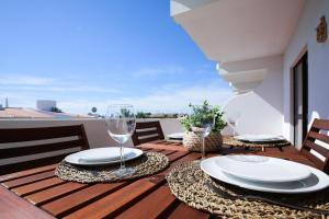 a wooden table with plates and glasses on a balcony at Sea Gardens - Alvaflor - Vilamoura in Vilamoura