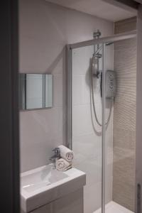 a white bathroom with a shower and a sink at Pres Pier Apartment - Bournemouth in Bournemouth