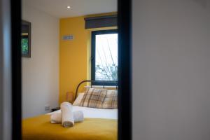 a bedroom with a bed with yellow walls and a window at Pres Pier Apartment - Bournemouth in Bournemouth