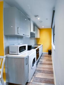 a kitchen with a washing machine and a microwave at Pres Pier Apartment - Bournemouth in Bournemouth