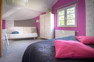 a bedroom with purple walls and a bed with pink pillows at B&B La maison de Régine in Jalhay
