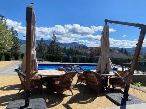 a patio with tables and umbrellas next to a pool at Under the Tree - Bed & Breakfast in Kelowna