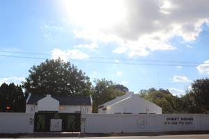 un edificio blanco con una valla delante en Thamani Guest House en Randfontein