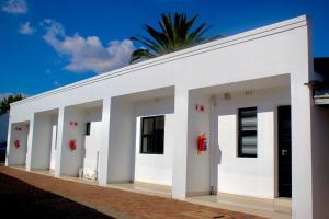 un edificio blanco con una palmera en el fondo en Thamani Guest House en Randfontein