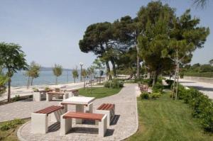a group of picnic tables and benches near the water at Apartments Brčić in Kaštela