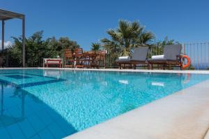 a swimming pool with blue water and two chairs at Dalasvillas SkalaMare in Skala