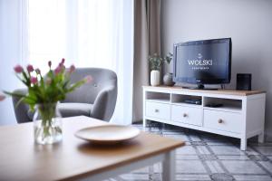 uma sala de estar com uma televisão num armário branco em Wolski Apartments - Reymonta 15 em Kolobrzeg