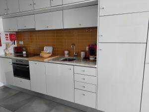 a kitchen with white cabinets and a sink at Acqua Marine in Sesimbra