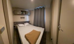 a small hospital room with a bed and a window at Mobil home climatisé 6 personnes dans camping 3* Tohapi a BOOFZHEIM in Boofzheim +5 photos