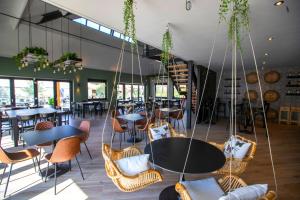 een restaurant met tafels, stoelen en ramen bij Papillon Country Resort in Denekamp