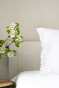 a white bed with a white pillow and a plant at Vija apartment Kuldīga in Kuldīga