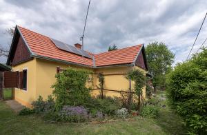 una casa amarilla con techo rojo con paneles solares. en Csavargó Tanya, en Szalafő