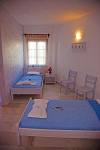 a bedroom with two beds and two chairs and a window at St.George Valsamitis in Katapola