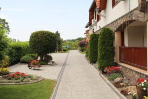 a walkway next to a building with flowers and a bench at Laura Villa in Veľký Meder