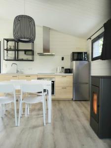 a kitchen with white tables and white chairs and a refrigerator at Chalet Little Cocoon in Tellin