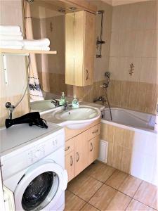 a bathroom with a sink and a washing machine at Center One Apartman in Debrecen