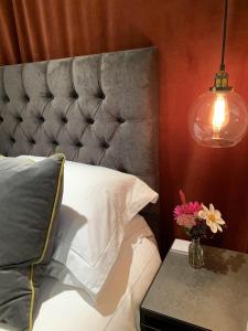 a bedroom with a bed with a gray headboard and a lamp at Bootmenders B&B in Petersfield