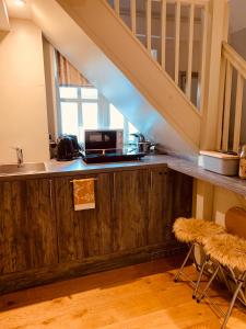 a kitchen with a counter with a sink and a staircase at Bootmenders B&B in Petersfield