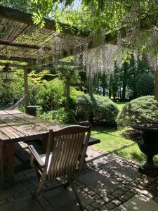 un banco de madera sentado bajo una pérgola junto a una mesa en Bootmenders B&B en Petersfield