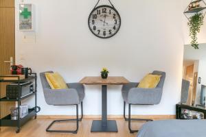 einen Tisch mit zwei Stühlen und eine Uhr an der Wand in der Unterkunft Spirit Apartments - Neben dem Titlis - Parkplatz in Engelberg