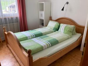 łóżko z zielonymi i białymi kocami i poduszkami w obiekcie Chalet Wildbach w mieście Adelboden
