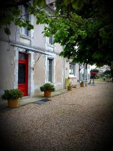 uma porta vermelha num edifício com vasos de plantas em B&B chez Annie em Saint-Martin-de-Gurçon