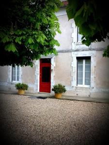 a red door on the side of a building at B&B chez Annie in Saint-Martin-de-Gurçon