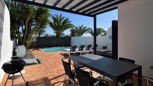 een patio met een tafel en stoelen en een zwembad bij Coloradas29 in Playa Blanca