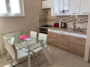 a kitchen with a glass table and white chairs at Center Piac Aparman in Debrecen