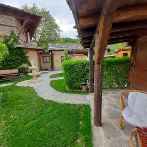 a garden with a bench and a stone walkway at Скендерова Къща Къщичка Алиса in Leshten