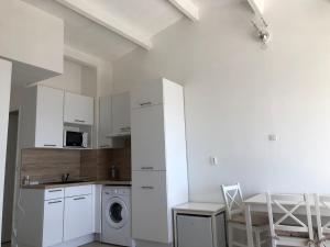 una cucina con mobili bianchi, lavatrice e asciugatrice di Appartement en 1ère ligne a Cap d'Agde