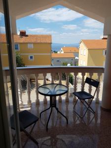 a balcony with a table and two chairs and a view at Apartmani Vrdoljak Malinska in Malinska