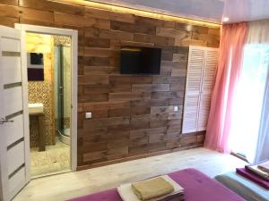 een badkamer met een houten muur en een tv. bij Эко отель Прованс Одесса in Odessa