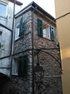 um antigo edifício de pedra com persianas verdes e uma luz de rua em Casa Ida em Monte Marcello