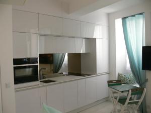 a kitchen with white cabinets and a table at Stone studio in Saint-Tropez