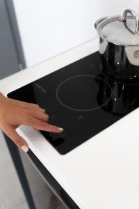 a hand on a stove with a pot on it at Seaside Suites in Kavos