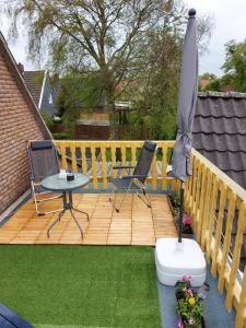 a wooden deck with an umbrella and a table and chairs at Ferienwohnung/Norden/4Personen in Norden