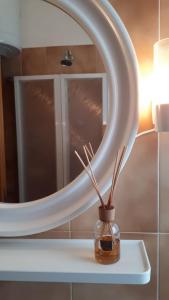 specchio da bagno con vaso e bastoncini di Alloggio Turistico IL Bucchero a Porto Clementino