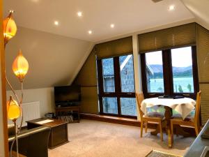 a living room with a table and some windows at Hunters Lodge Apartments in Ballachulish