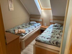 two twin beds in a small room with two tables at Boróka Apartman Gyula in Gyula