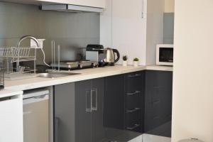 a kitchen with black cabinets and a microwave at Princess Luxury Suite 2 in Paralia Katerinis