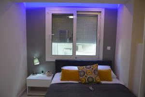 a bedroom with a bed and a window with purple lighting at Princess Luxury Suite 2 in Paralia Katerinis +35 photos