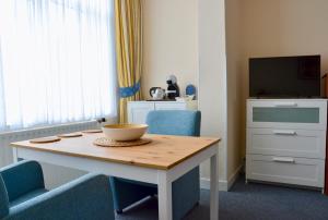 Zimmer mit einem Tisch, Stühlen und einem TV in der Unterkunft Hotel De Stern in Scheveningen