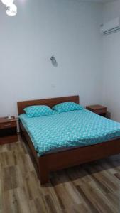 a bedroom with a bed with a blue comforter and two tables at Vržina Farm House Skadar Lake in Virpazar