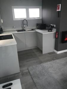 a kitchen with white counters and a sink and a window at 49 Cherry Park Chalet in Chapel Saint Leonards