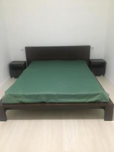 Una cama con una manta verde encima. en Guest house Amza, en Ochamchira