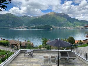 a patio with an umbrella and chairs and a lake at Residence Molinari Lake Como in Lezzeno
